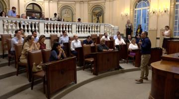 sala princesa isabel com secretários sentados e um deles em pé falando ao grupo. #paratodosverem 