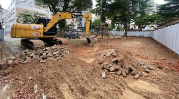 trator está cavando solo de terra em área tapumada. #paratodosverem 