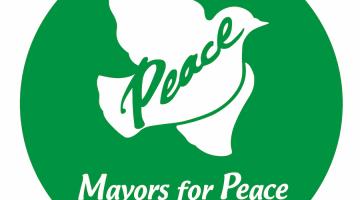 O logotipo da Mayors for Peace, com uma pomba ao centro e a palavra Peace. #Paratodoslerem