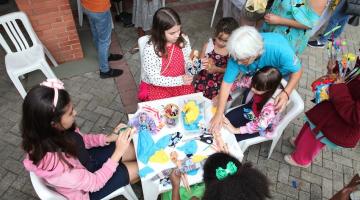 crianças pintando em mesa no parque #paratodosverem