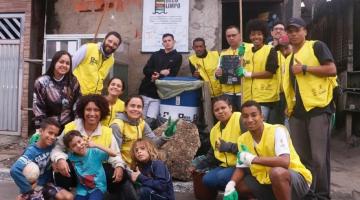 jovens uniformizados e reunidos para foto. Na casa ao fundo está afixada uma placa onde se lê Beco Limpo. #paratodosverem