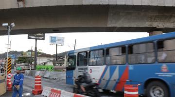 Ônibus municipal passa em via sob viaduto. #Paratodosverem