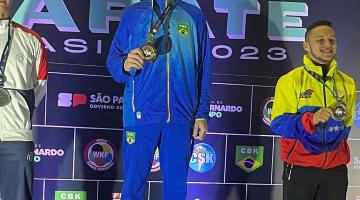 matheus está no primeiro lugar do pódio com a medalha no peito e a mão direita na medalha. #paratodosverem