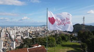 Bandeira da ação hasteada no alto do Monte Serrat com cidade ao fundo. #paratodosverem
