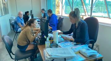 pessoas em torno de mesas com documentos. #paratodosverem