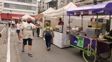 barracas de lanches montadas em praça. Pessoas circulam em torno. #paratodosverem