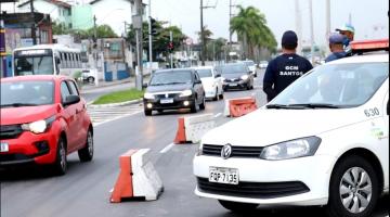 Viatura parada na via ao lado de cones que demarcam a pista. Guarda municipal e outros aguentes olham para o movimento de veículos. #Paratodosverem