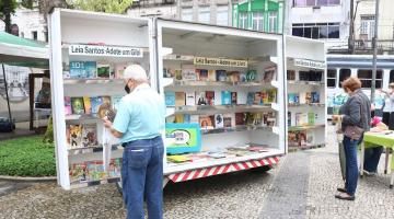 Duas pessoas olham livros e gibis em estande do Leia Santos #paratodosverem