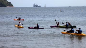 No mar, várias pessoas praticando canoagem. #paratodosverem