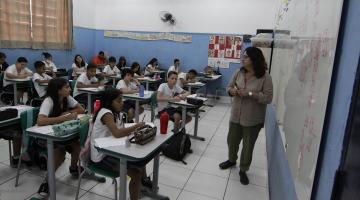 sala de aula com alunos sentadas e professora à frente da lousa. #paratodosverem 