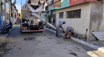 dois homens trabalham na construção de guias em rua. #paratodosverem