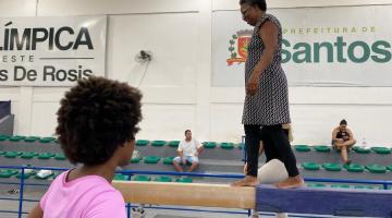 menina olha a mãe na trave de equilíbrio.#paratodosverem