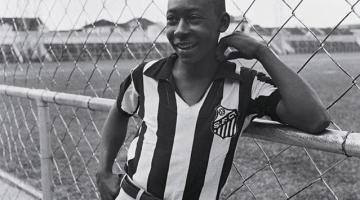 Pelé ainda jovem com camisa do Santos encostado no alambrado #paratodosverem