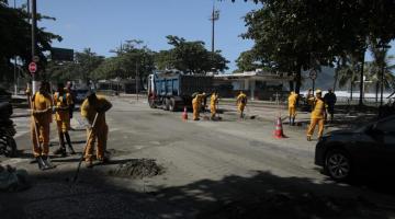 Homens removem areia de pista afetada por alagamento na Ponta da Praia. #Paratodosverem