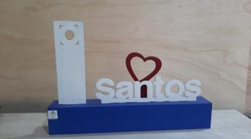 miniatura de toten com mureta decorativa e ao lado, a palavra santos com um coração. #paratodosverem