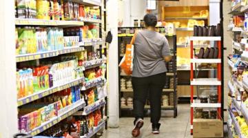 Mulher com sacola no corredor de um supermercado. #paratodosverem