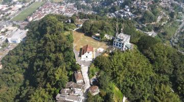 vista aérea do monte serrat, com a capela ao centro e o antigo cassino ao fundo. Área é rodeada de verde. #paratodosverem