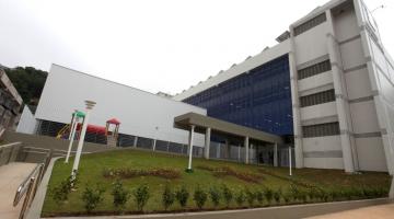 Fachada lateral da escola, com jardim gramado à frente. #Pracegover