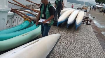 agentes caminham próximo a canoas com bocas viradas para baixo na ponta da praia. #paratodosverem