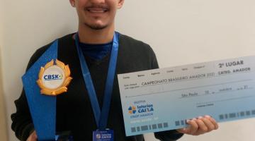 Atleta exibe troféu e cheque #paratodosverem