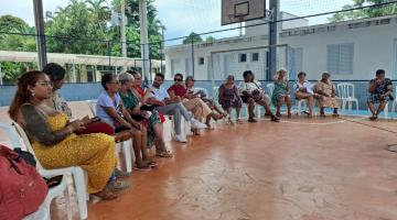pessoas sentadas para reunião em quadra esportiva. #paratodosverem
