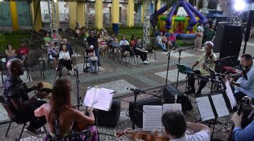 apresentação de conjunto de cordas e público ao fundo em um espaço aberto. #paratodosverem 