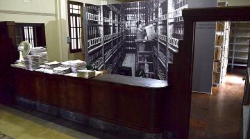 interior de prédio com documentos sobre um móvel antigo. #paratodosverem 