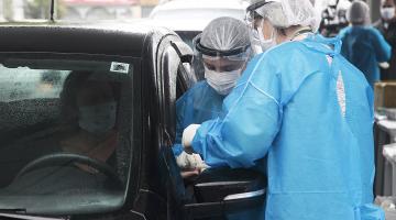 duas técnicas da saúde coletam exame de mulher ao volante de carro #paratodosverem 