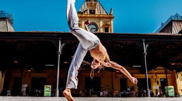 homem faz movimento de capoeira na frente da estação do valongo #paratodosverem 