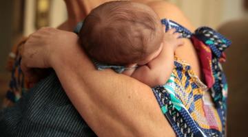 Bebê sendo abraçado e no colo de uma mulher. #paratodosverem
