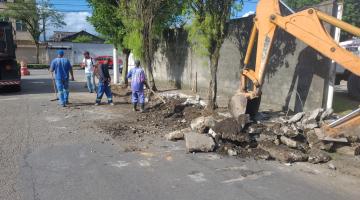 homens trabalhando e escavadeira removendo guias e sarjetas de rua. #paratodosverem