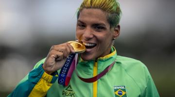 Atleta com agasalho do Brasil morde medalha de ouro #paratodosverem