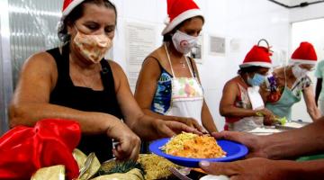 voluntários com toca de papai noel servem comida #paratodosverem