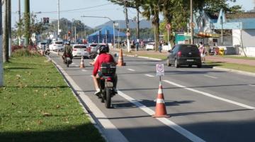 Moto está em faixa à esquerda de pista, em trecho sinalizado por cones. #Paratodosverem 