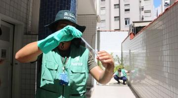 agente uniformizado olha tubo com larvas #paratodosverem