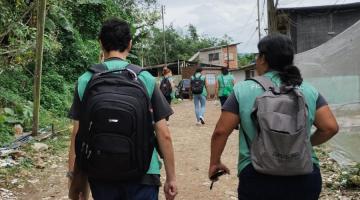 agentes uniformizados caminham por rua de terra. #paratodosverem 