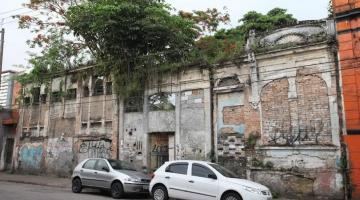 terreno em rua com muro na frente e dois carros parados na via. #paratodosverem