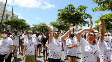 Grupo caminha pela avenida da orla debaixo de sol e vestido com camisas alusivas à prevenção do HIV. #pracegover