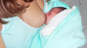 Bebê é amamentado no peito. #paratodosverem