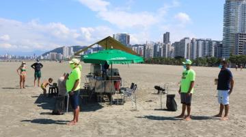 Ambulantes ao lado de um carrinho na praia #paratodosverem