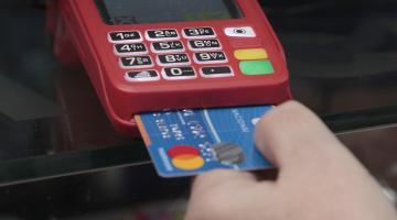 Mão de mulher insere cartão em máquina de crédito/débito - #Pracegover