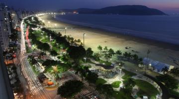 imagem aérea da praia, jardins, avenida e prédios a noite #paratodosverem