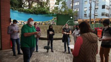 professor fala aos alunos, em pé e em círculo na entrada do orquidário