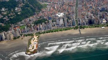 Foto área de Santos aparecendo praia, areia, prédios e morro. #paratodosverem