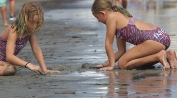 crianças brincam na areia da praia #paratodosverem