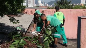 Homens uniformizados retiram folhas de calha. #Paratodosverem