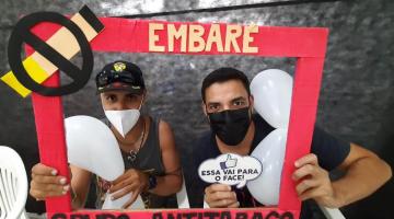 dois rapazes seguram uma moldura onde se lê no alto Embaré. Ao lado, a arte de um cigarro com um carimbo para não fumar. Na parte de baixo se lê grupo antitabaco. #paratodosverem