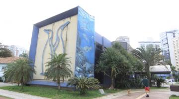 fachada lateral do parque com ilustração em relevo de dois pinguins em uma face e uma arte sobre o oceano na empena direita. #paratodosverem