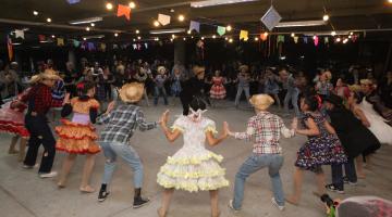 grupo com roupas típicas juninas dança quadrilha. #paratodosverem