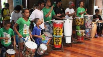 Crianças e jovens tocam instrumentos de percussão. #Paratodosverem